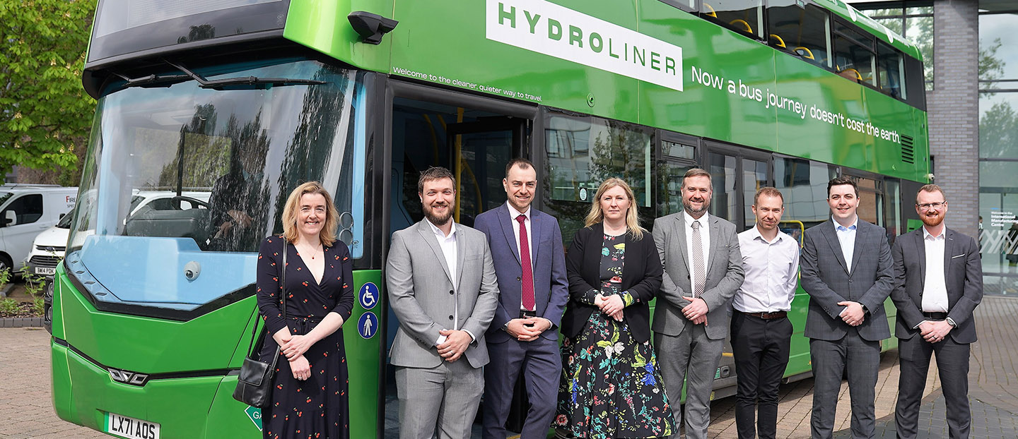 Group standing in front of Green Hydroliner bus