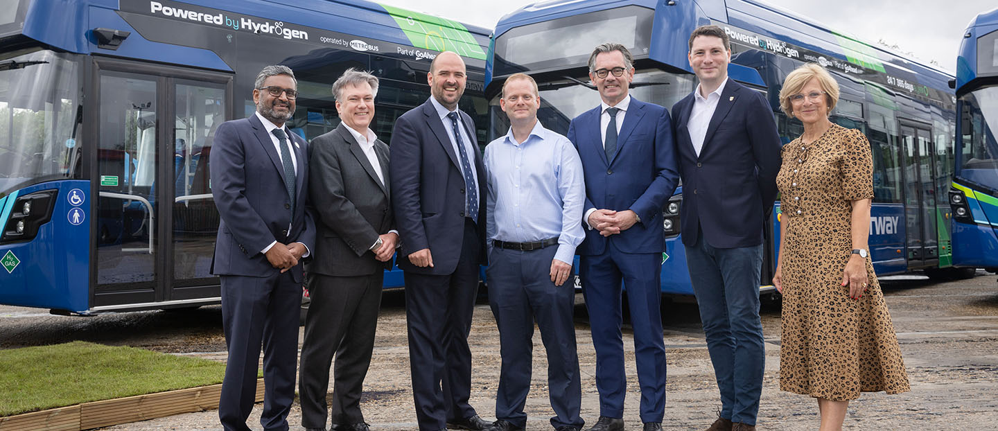 group of people standing in front of hydrogen single deck bus