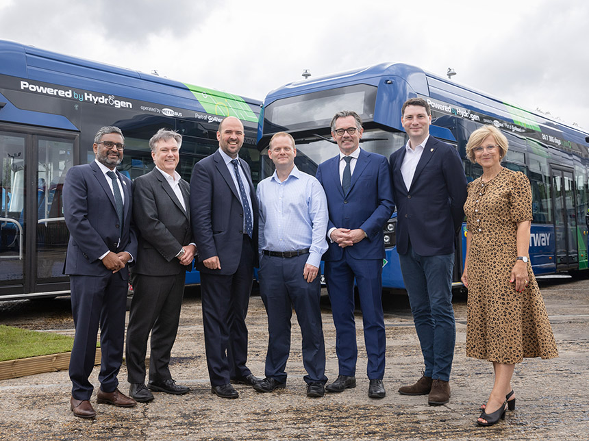 group of people standing in front of hydrogen single deck bus