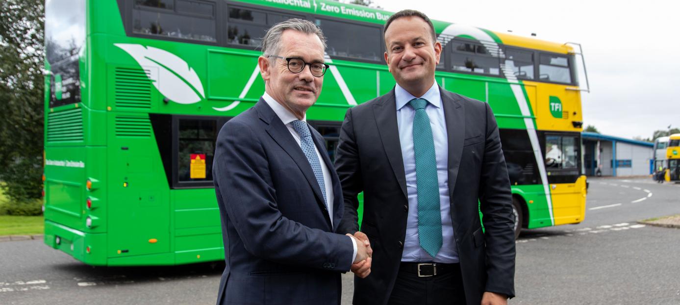 Taoiseach Leo Varadkar and Jean-Marc Gales shaking hands in front of a green and yellow double deck bus