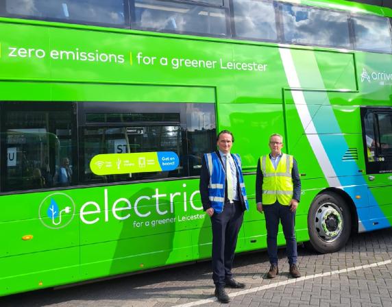 men standing in front of a green double deck bus