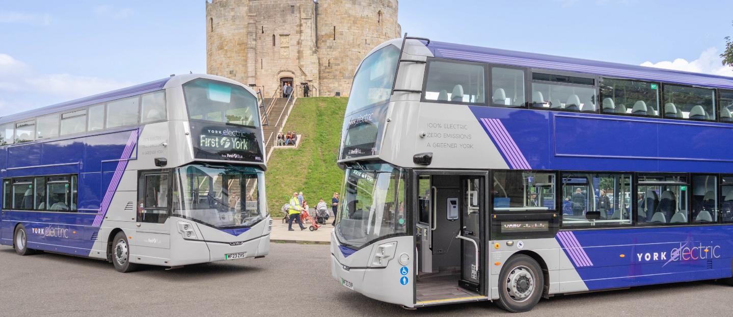 grey and purple double deck buses parked in front of a castle