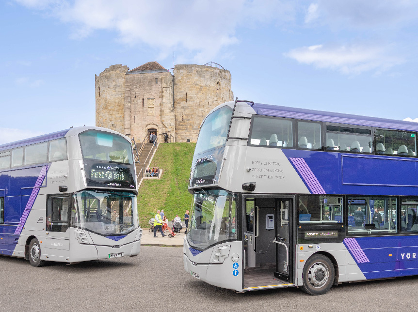 grey and purple double deck buses parked in front of a castle