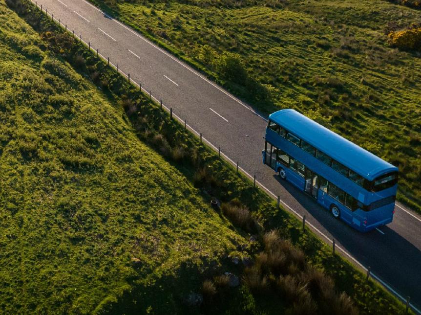 blue double deck bus driving along a country road, photograph has been taken by a drone