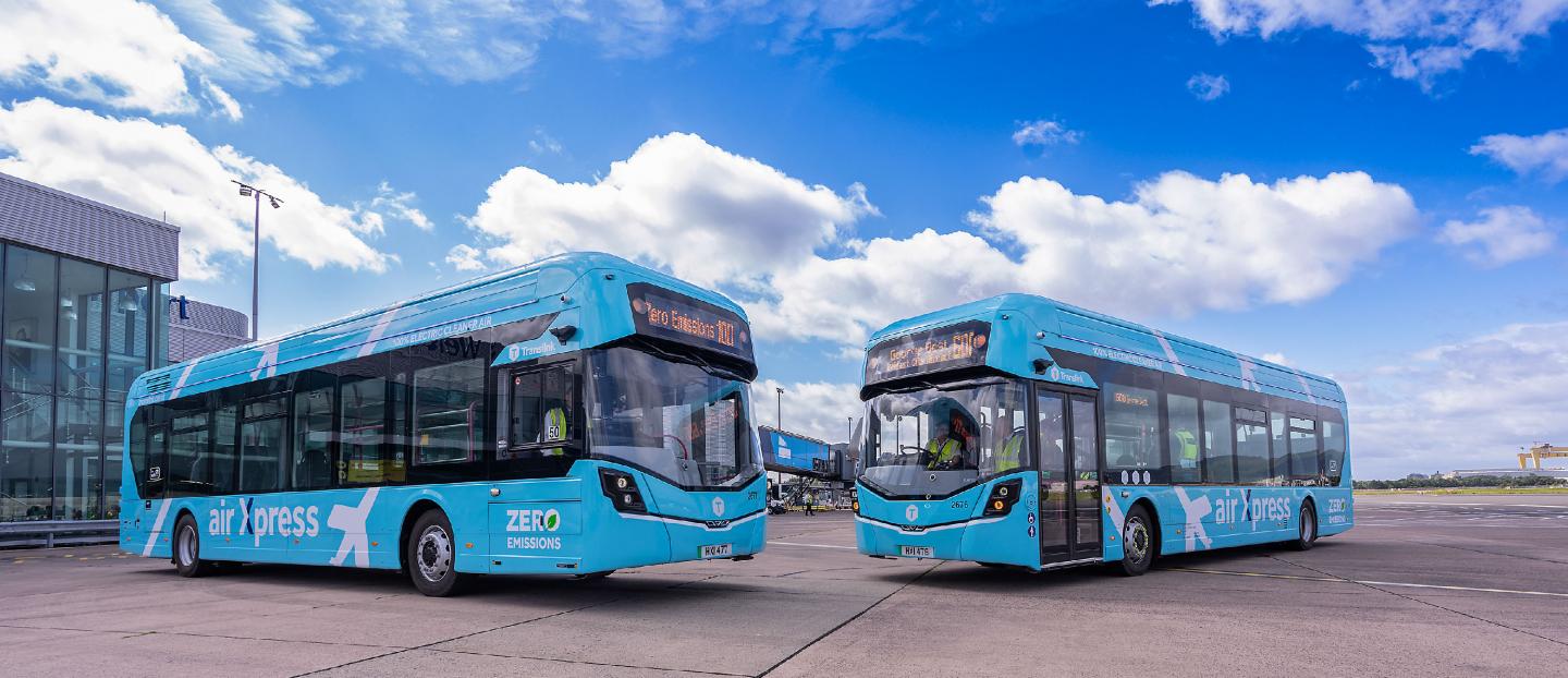 two airport buses parked on the runway on a sunny day