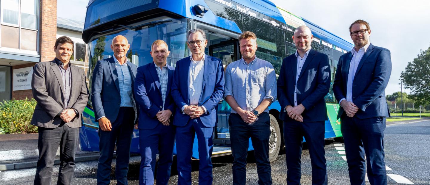 Senior team from Go-Ahead and Wrightbus standing in front of a blue single deck hydrogen bus at the Wrightbus factory in Ballymena