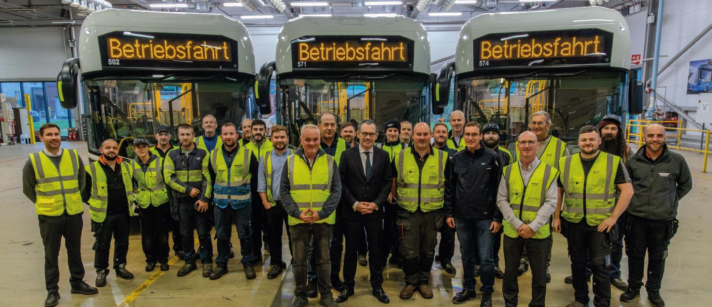 Jean-Marc Gales with representatives from RVK and Wrightbus team standing in front of three RVK buses in the Ballymena factory