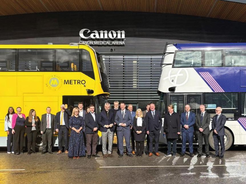 line up of senior leaders from Wrightbus and government and local authority figureheads at the UK’s first bus manufacturing panel. The group are standing in front of 2 double deck buses