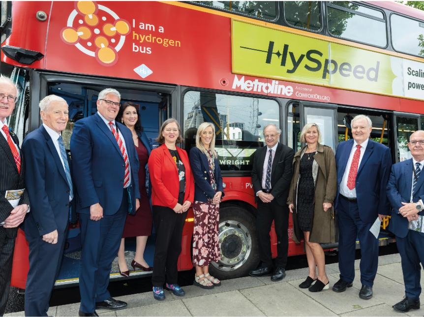 Group of leaders standing in front of a red double deck bus at Westminster