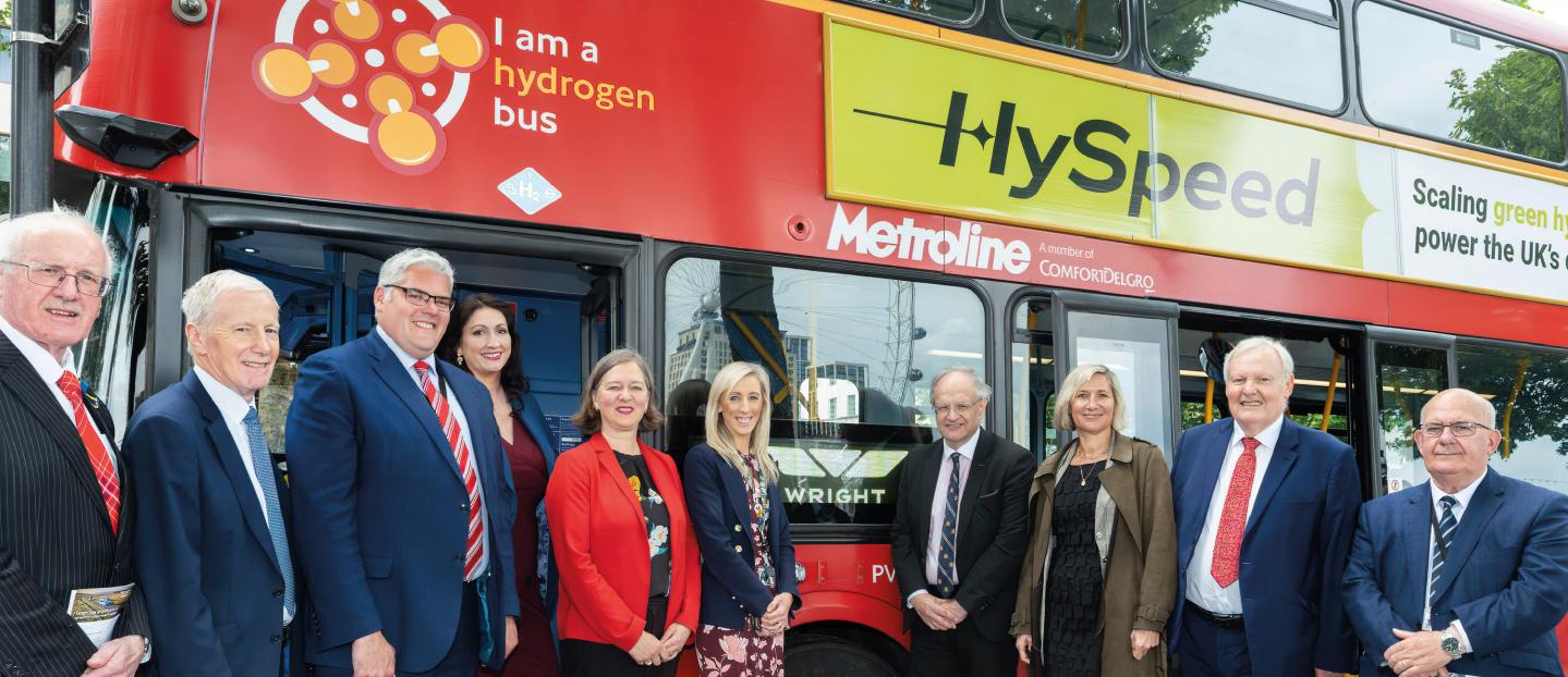 Group of leaders standing in front of a red double deck bus at Westminster