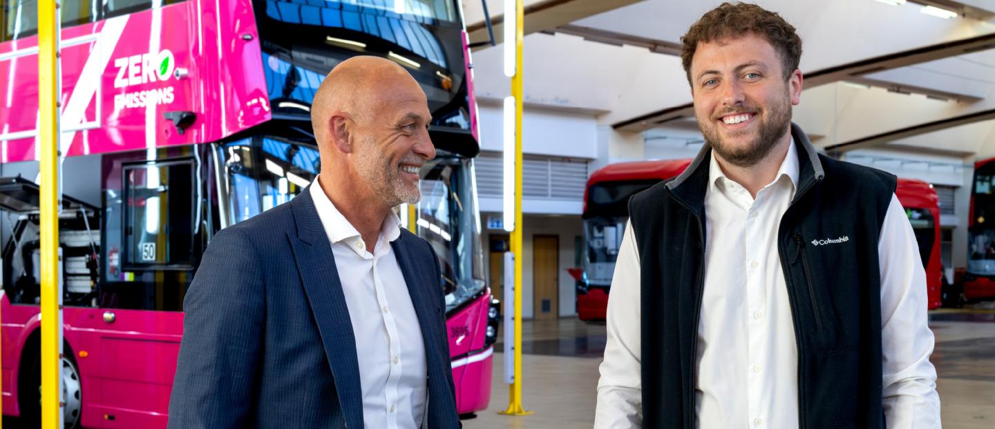 men standing side by side in a bus factory