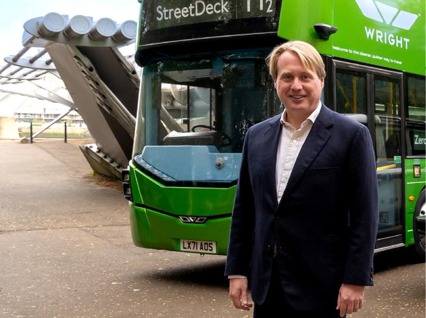 Jo Bamford CBE standing in front of a hydrogen double deck bus from Wrightbus