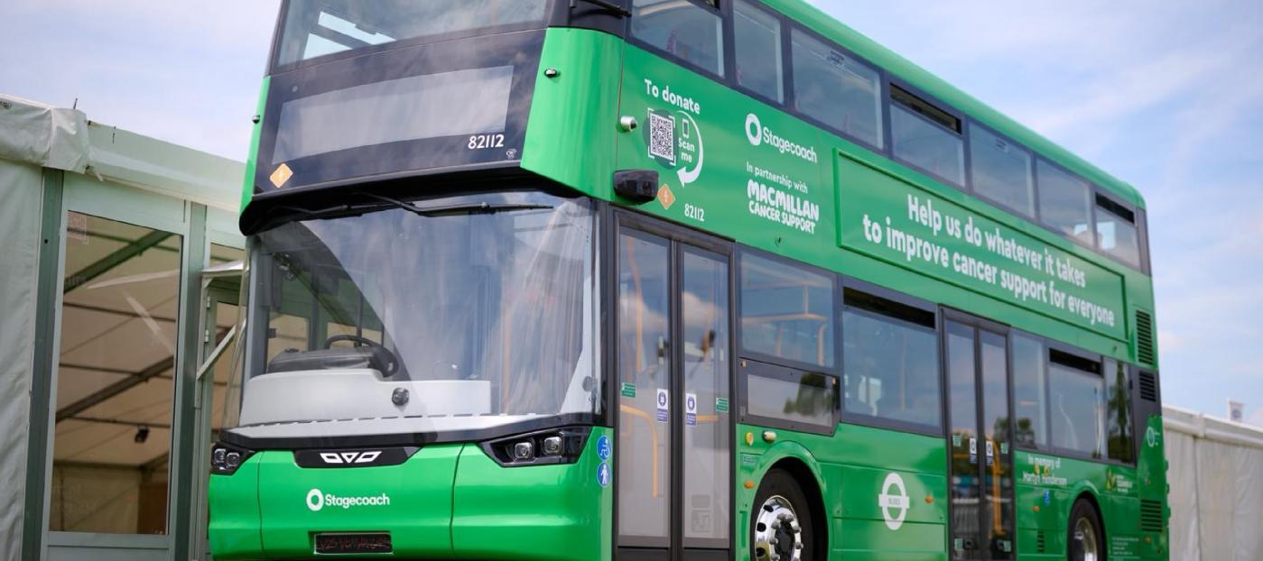 a green double deck bus with livery messaging and branding for Macmillan Cancer Support