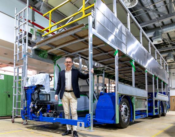 Jean-Marc Gales standing inside the frame of a double deck bus chassis