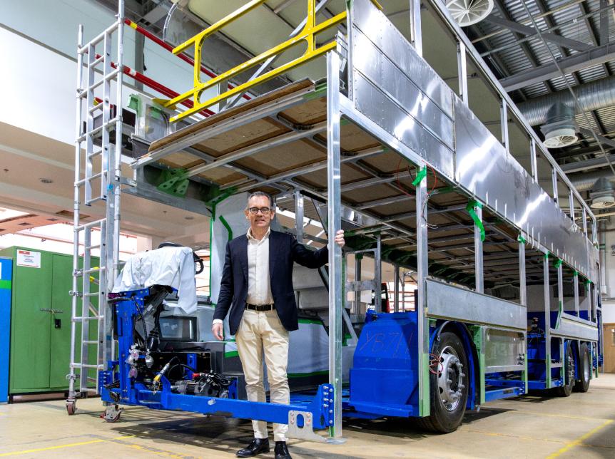 Jean-Marc Gales standing inside the frame of a double deck bus chassis