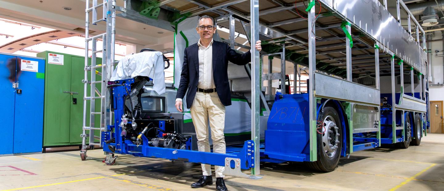Jean-Marc Gales standing inside the frame of a double deck bus chassis