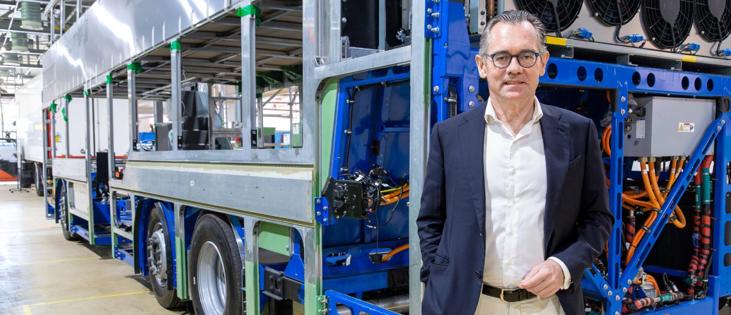 Jean-Marc Gales standing beside a bus chassis inside factory