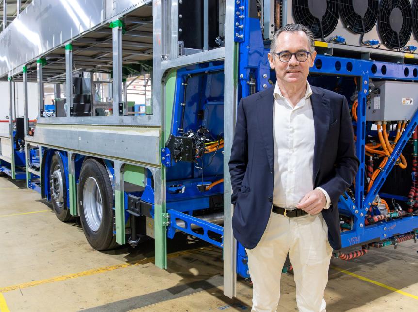 Jean-Marc Gales standing beside a bus chassis inside factory