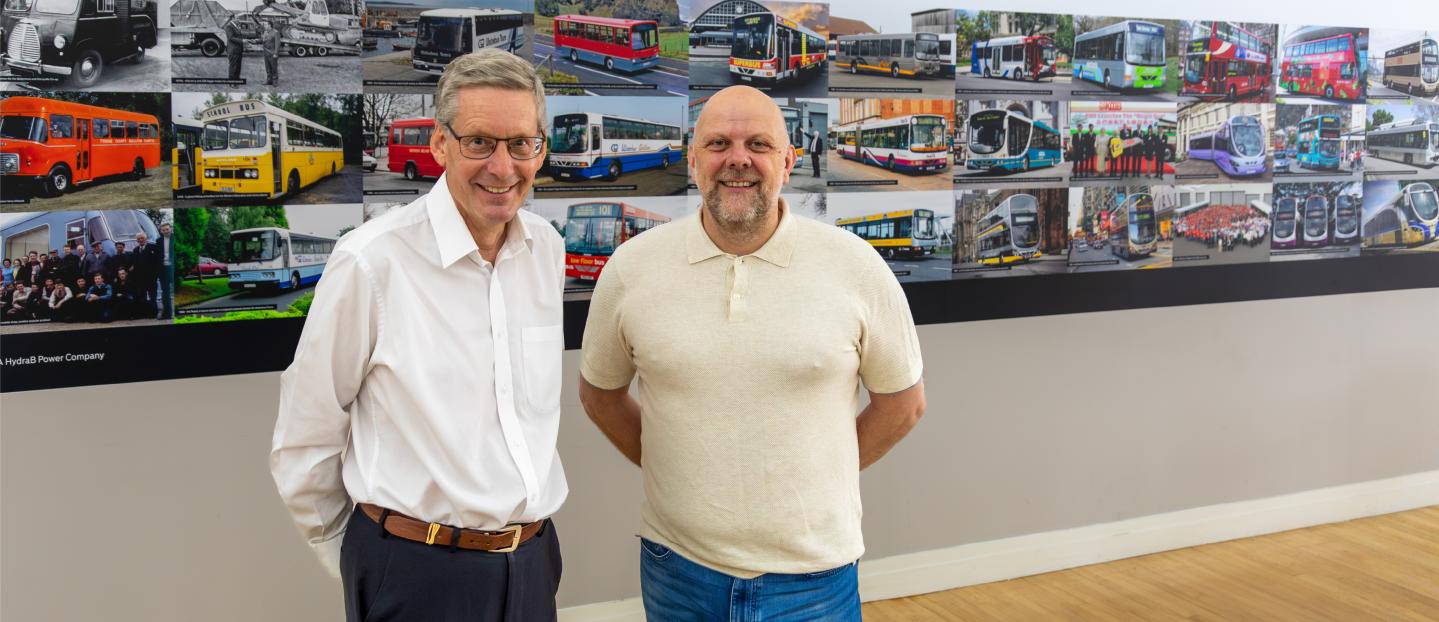 Christian Reynolds and Paul Savage with Wrightbus 80th wall photo montage